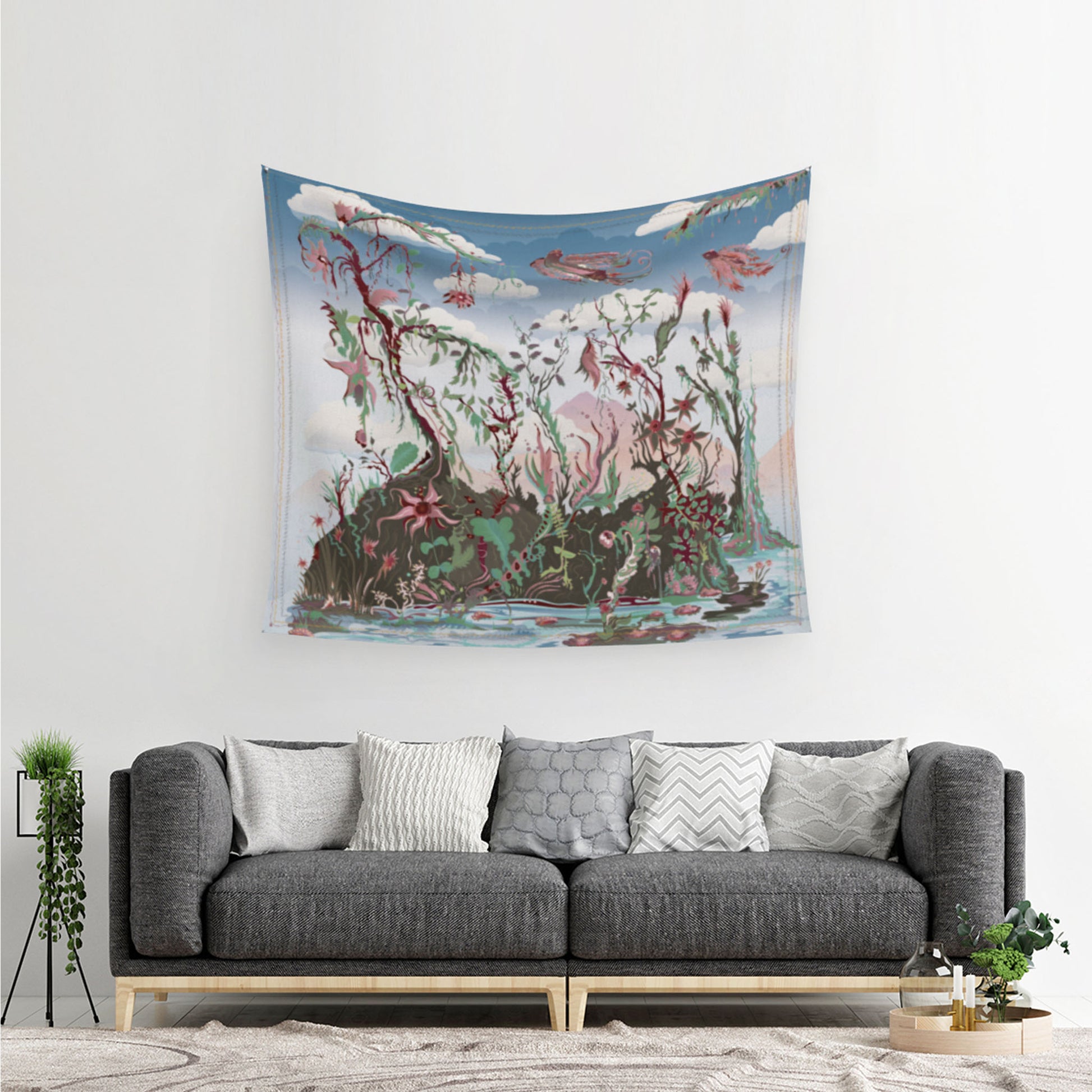 mockup for digital design for tapestry showing the hummingbird queen being followed closely by the hummingbird king over an imaginary land of plants and trees, all beneath a cloud cover the tapestry is hanging over a couch with many pillows and a couch to illustrate how to use a tapestry