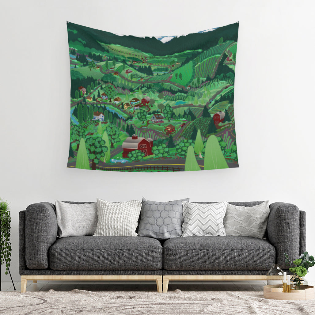 mockup for tapestry on wall with digital design showing the way mountain roads and farms roads coincide as the hills roll up and down around farmhouses, surprised barns, fruitful fields and fruit trees all bursting with Mother Nature's many shades of green hanging above a comfy looking couch with five random pillows relaxing